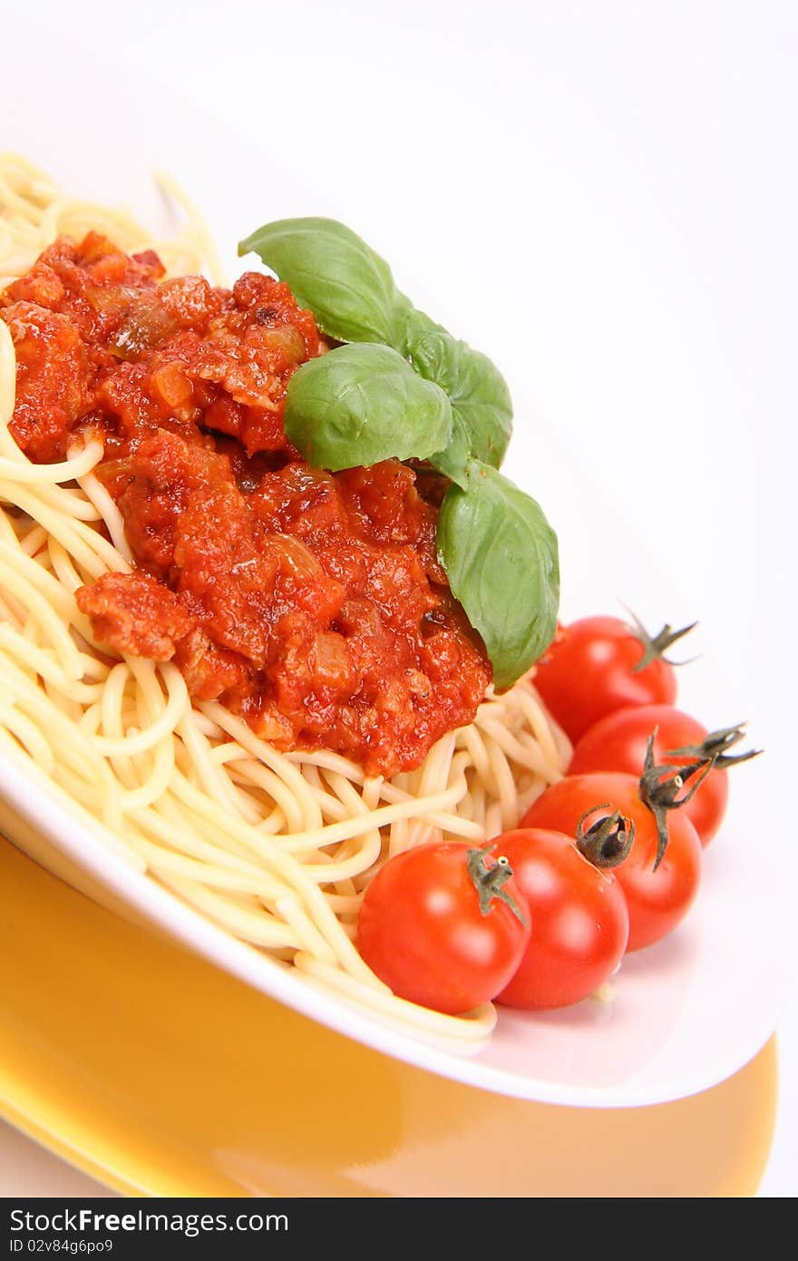 Spaghetti Bolognese on a plate decorated with fresh basil and cherry tomatoes in close up