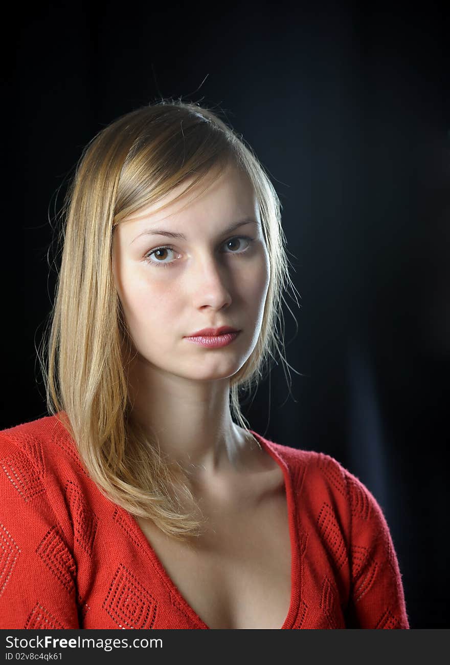 Portrait of young blonde girl in red on black background. Portrait of young blonde girl in red on black background