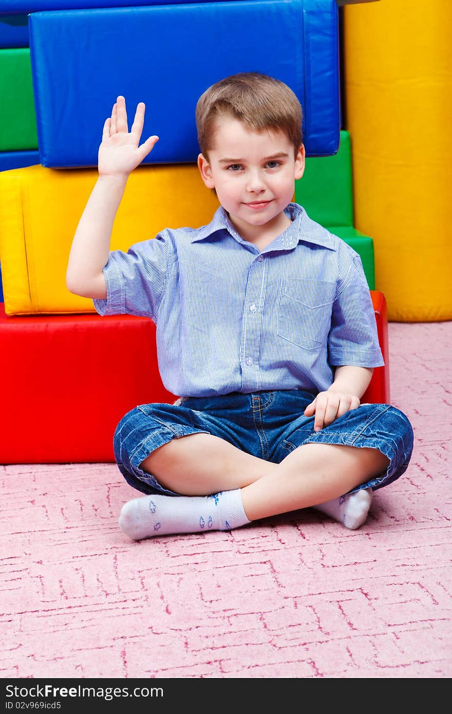 Handsome kid sitting in front of large colorful blocks