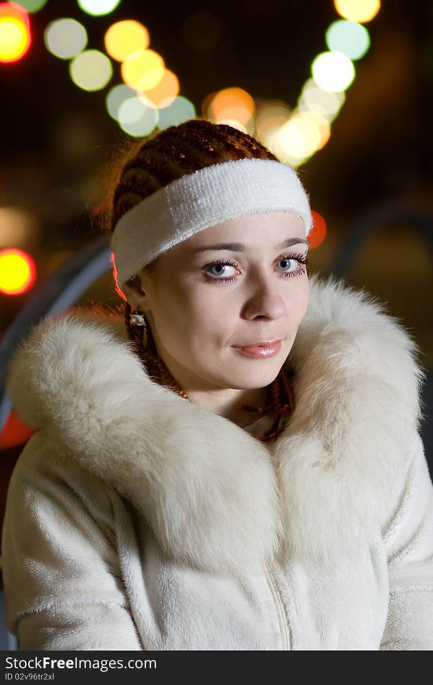 Portrait of a fashionable teenage girl in white fur coat outdoors at night. Portrait of a fashionable teenage girl in white fur coat outdoors at night