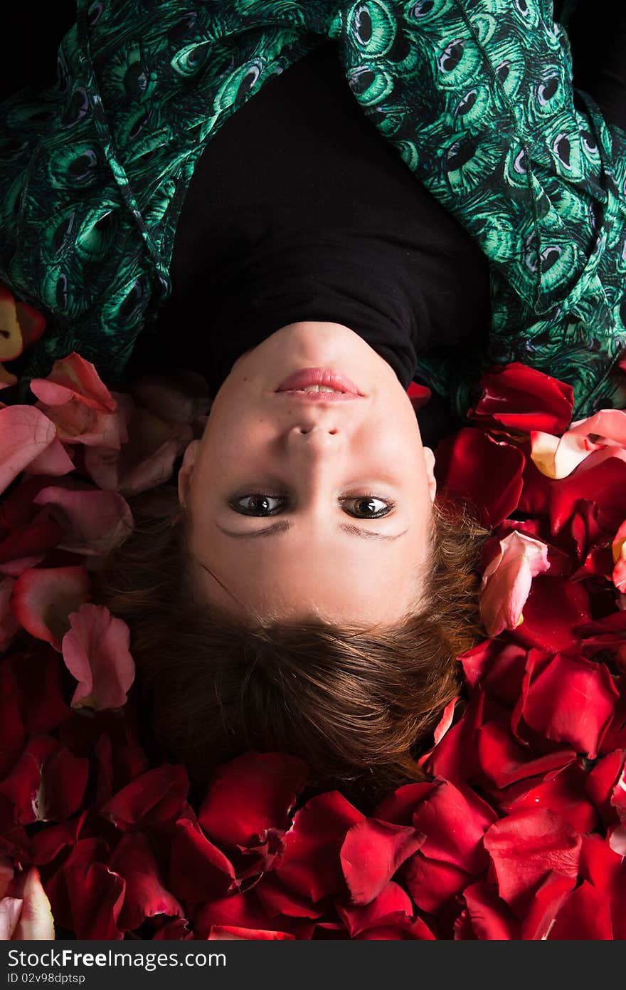 Attractive young woman lying amongst rose petals. Attractive young woman lying amongst rose petals