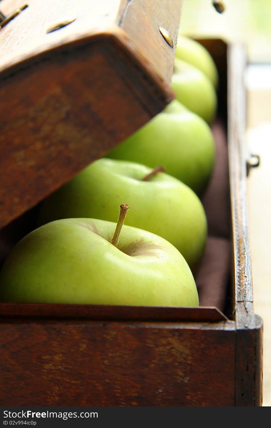 Green apples on the background of an old wooden chest