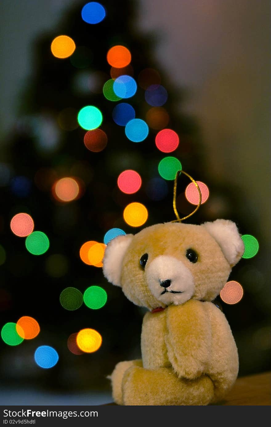 A christmas ornament looking sad with tree out of focus in background. A christmas ornament looking sad with tree out of focus in background