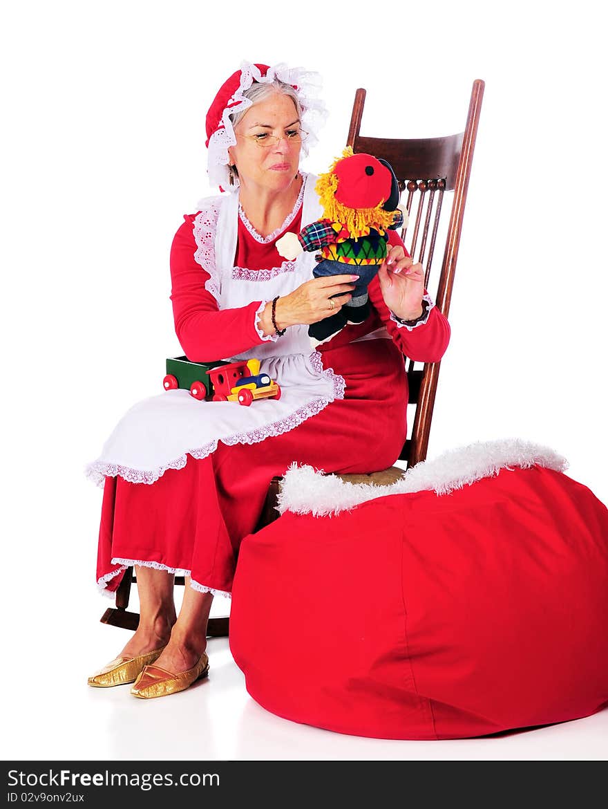 Mrs. Santa Claus admiring the toys while stuffing Santa's sack.  Isolated on white. Mrs. Santa Claus admiring the toys while stuffing Santa's sack.  Isolated on white.