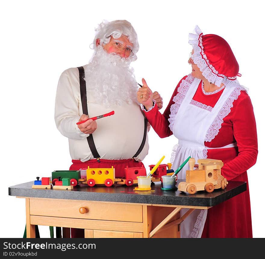 Mrs. Claus giving Santa a thumbs up as he paints toys for Christmas. Isolated on white. Mrs. Claus giving Santa a thumbs up as he paints toys for Christmas. Isolated on white.