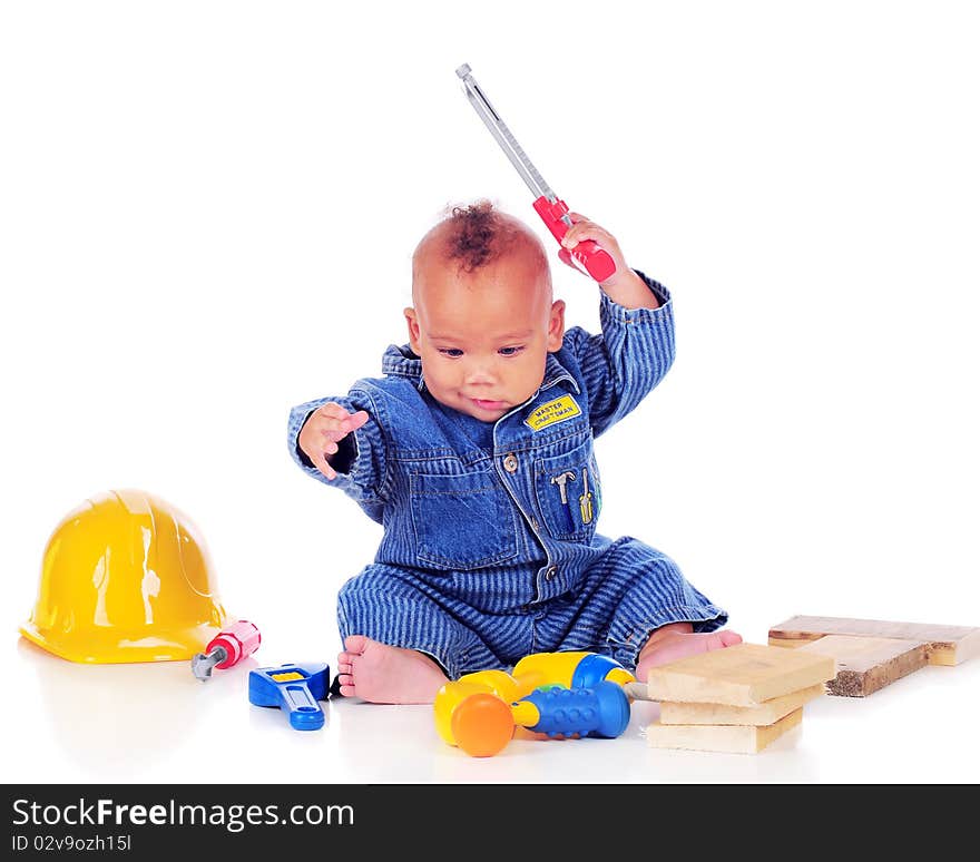 An adorable biracial baby weilding a handsaw while playing with toy tools and wearing craftsman overalls. Isolated on white. An adorable biracial baby weilding a handsaw while playing with toy tools and wearing craftsman overalls. Isolated on white.