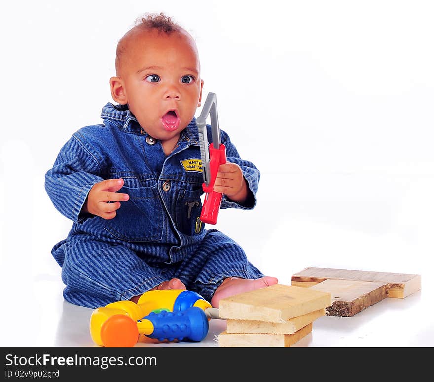 An adorable biracial baby ready to go at blocks of wood with a toy handsaw. Isolated on white. An adorable biracial baby ready to go at blocks of wood with a toy handsaw. Isolated on white.