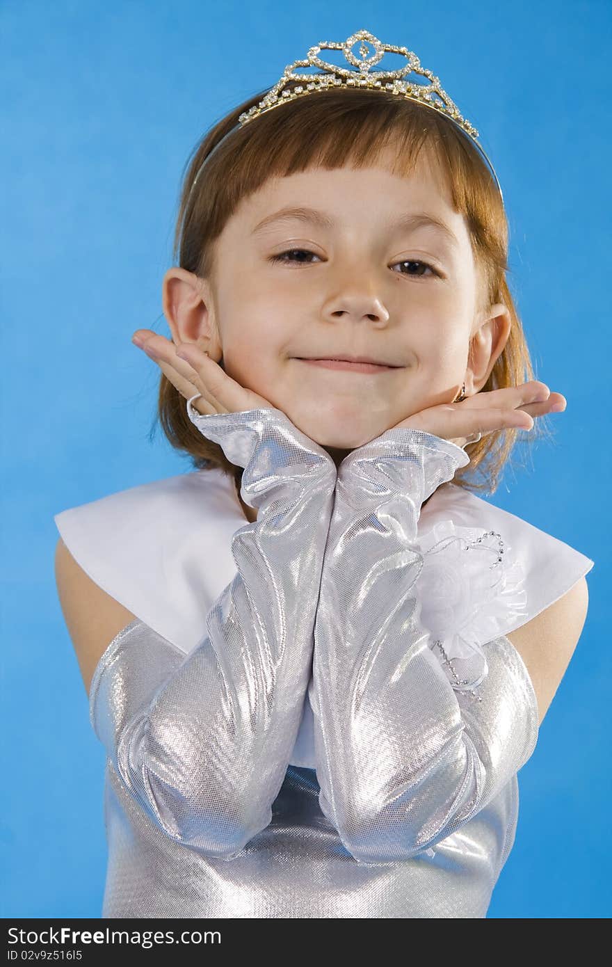 The girl the princess in a white dress sits opposite to a blue background. The girl the princess in a white dress sits opposite to a blue background