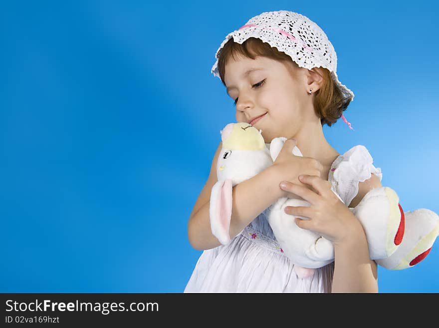 Little girl plays with a soft toy. A blue background. Little girl plays with a soft toy. A blue background.