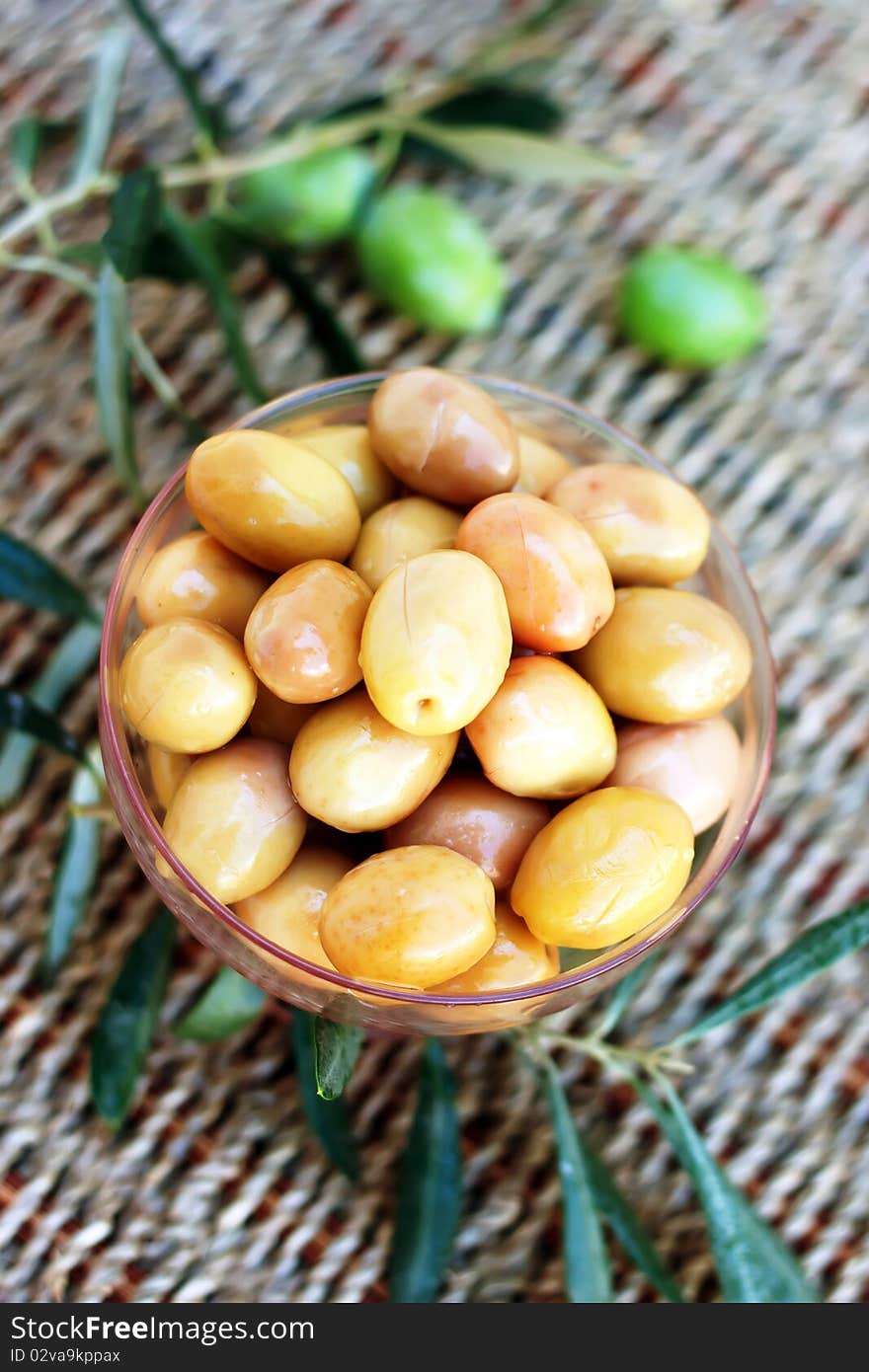 Green olives with leaves on cane background