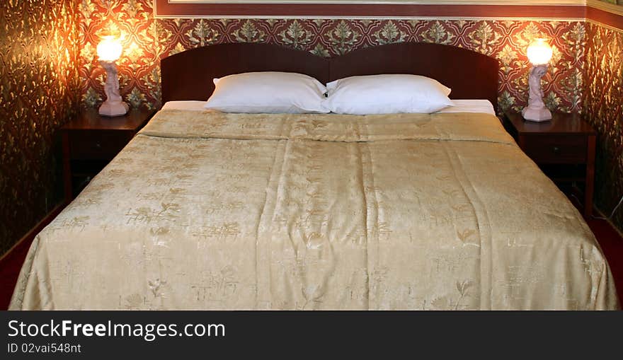 Bed with two pillows and lamps in the room with red wall