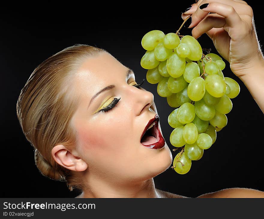 Beautiful woman with bright make-up holding green grapes. Beautiful woman with bright make-up holding green grapes