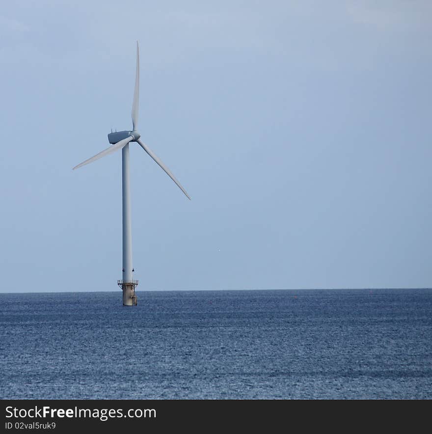 A Single Wind Turbine Tower Standing in the Sea.