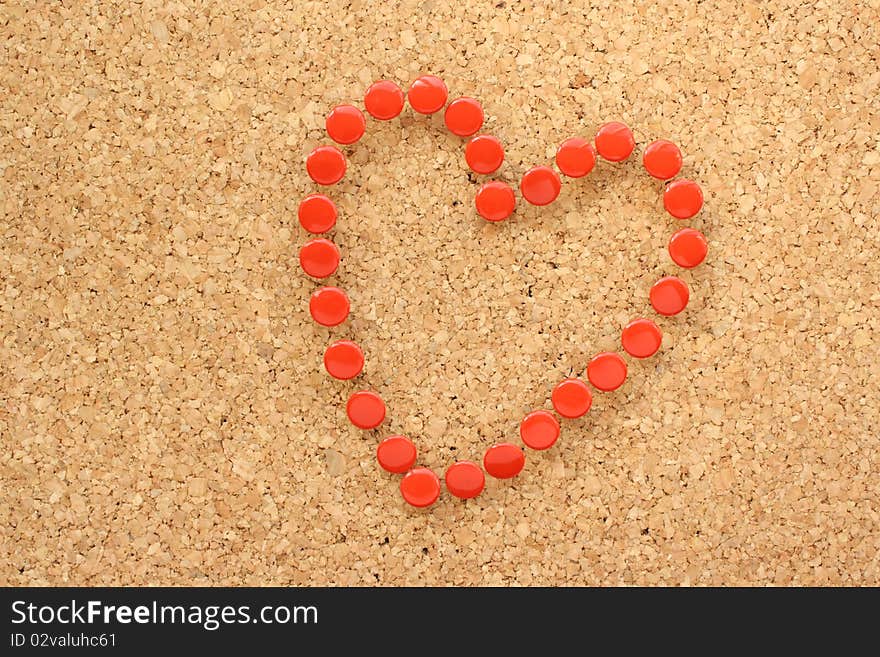 Heart shaped symbol created from red drawing pins on a cork notice board. Heart shaped symbol created from red drawing pins on a cork notice board