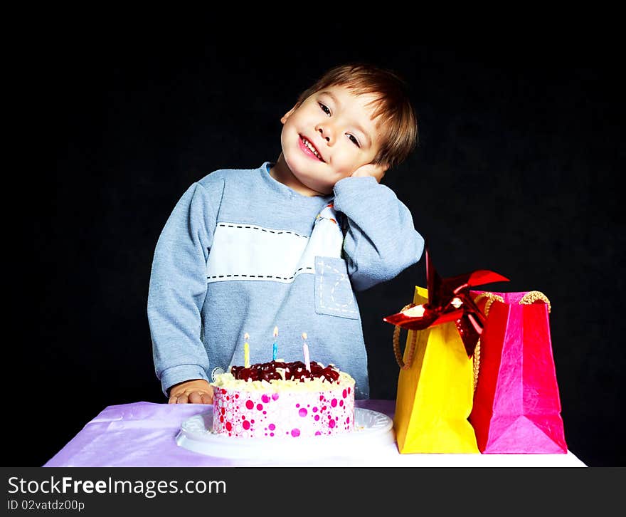 Cute three year old baby celebrating his birthday and blowing off the candles on the cake. Cute three year old baby celebrating his birthday and blowing off the candles on the cake