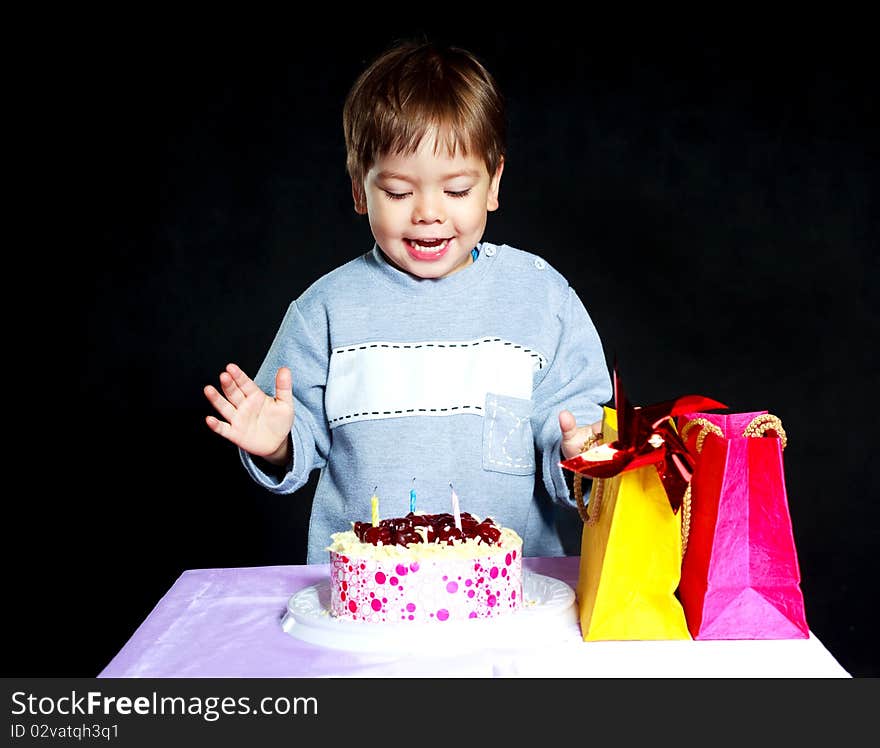 Cute three year old baby celebrating his birthday and blowing off the candles on the cake. Cute three year old baby celebrating his birthday and blowing off the candles on the cake