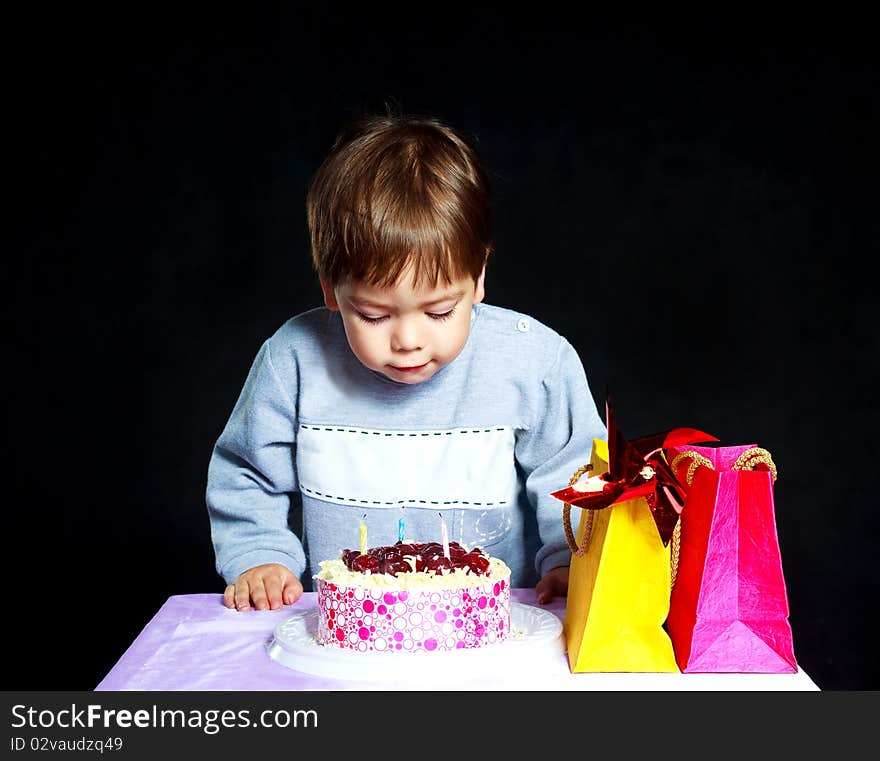 Cute three year old baby celebrating his birthday and blowing off the candles on the cake. Cute three year old baby celebrating his birthday and blowing off the candles on the cake