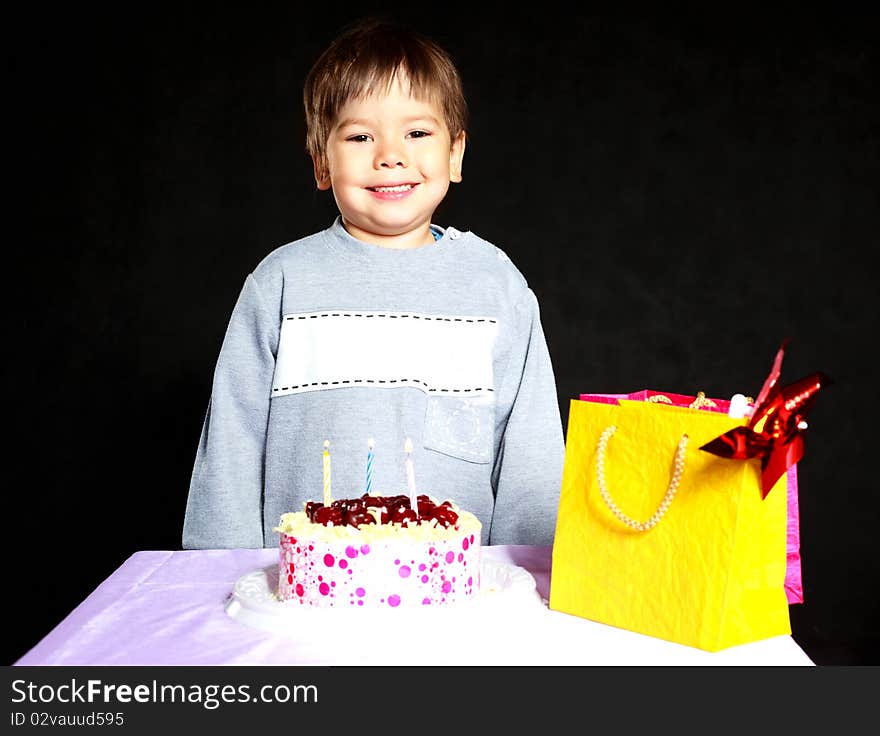 Cute three year old baby celebrating his birthday and blowing off the candles on the cake. Cute three year old baby celebrating his birthday and blowing off the candles on the cake