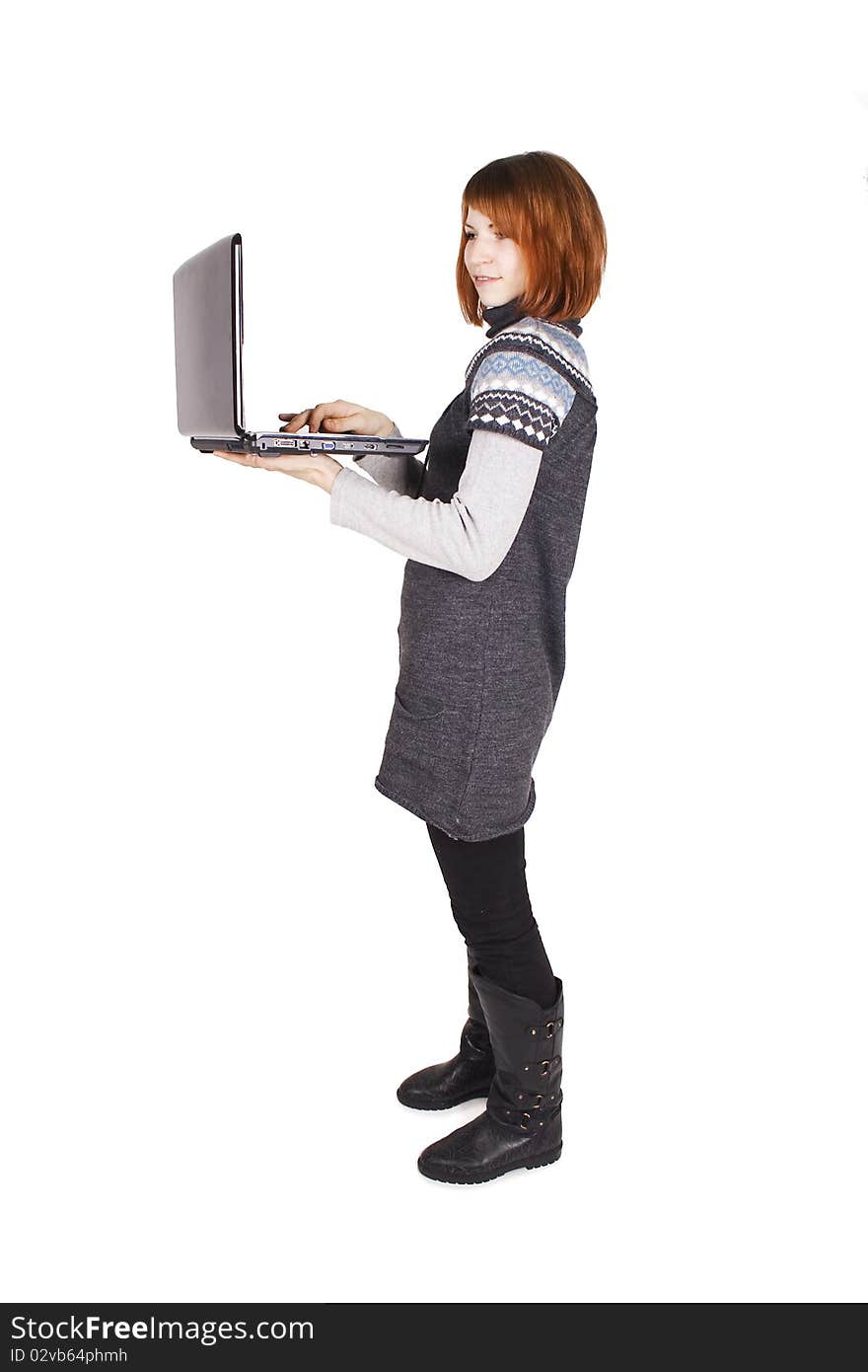 Young beautiful girl in knit dress standing with laptop, isolated on white