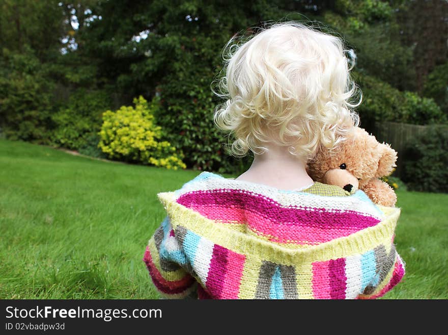 Small girl cuddling teddy in the garden. Small girl cuddling teddy in the garden