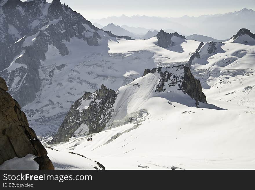 From the summit of l'Aiguille du Midi (3,842 m), the views of the Alps are spectacular. In this picture, you can see the panoramic funicular leading to a peak in Italy. From the summit of l'Aiguille du Midi (3,842 m), the views of the Alps are spectacular. In this picture, you can see the panoramic funicular leading to a peak in Italy