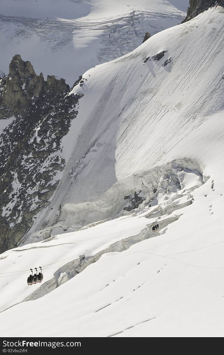 From the summit of l'Aiguille du Midi (3,842 m), the views of the Alps are spectacular. In this picture, you can see the panoramic funicular leading to a peak in Italy. From the summit of l'Aiguille du Midi (3,842 m), the views of the Alps are spectacular. In this picture, you can see the panoramic funicular leading to a peak in Italy