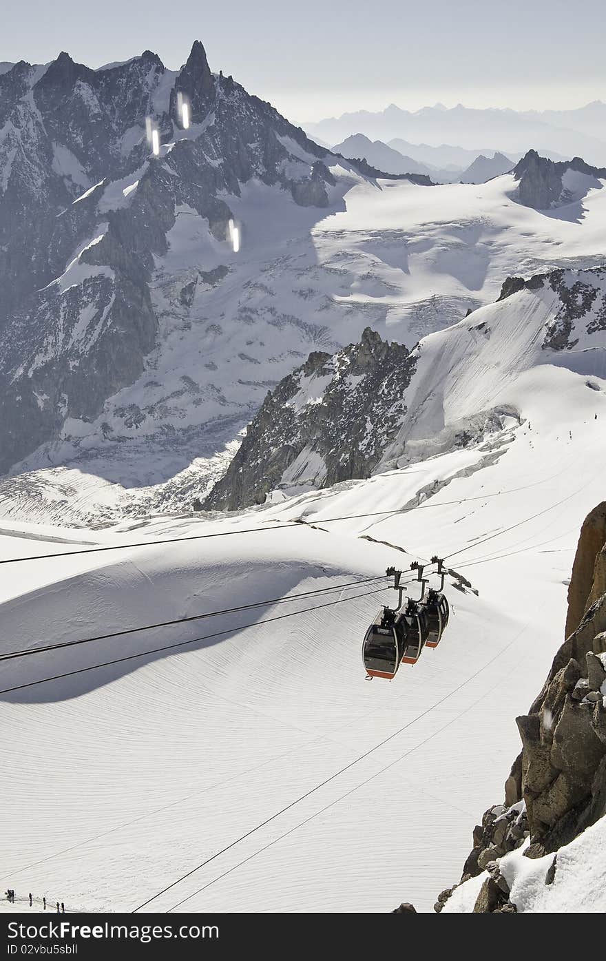 From the summit of l'Aiguille du Midi (3,842 m), the views of the Alps are spectacular. In this picture, you can see the panoramic funicular leading to a peak in Italy. From the summit of l'Aiguille du Midi (3,842 m), the views of the Alps are spectacular. In this picture, you can see the panoramic funicular leading to a peak in Italy