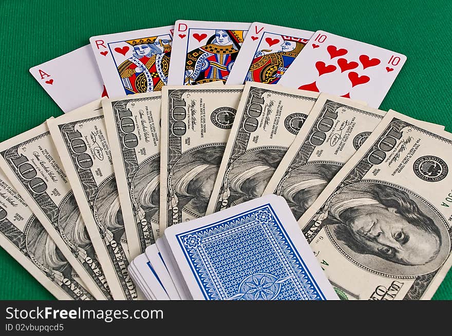 Poker cards showing royal flush and dollars on green cloth