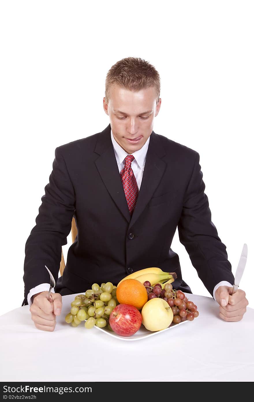 A man sitting at the table getting ready to dig into his plate of fruit while he licks his lips. A man sitting at the table getting ready to dig into his plate of fruit while he licks his lips.