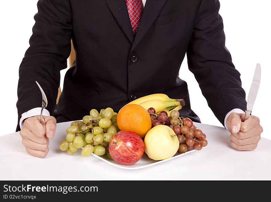 A close up view of a man holding his fork and knife getting ready to dig into a plate of fruit. A close up view of a man holding his fork and knife getting ready to dig into a plate of fruit.