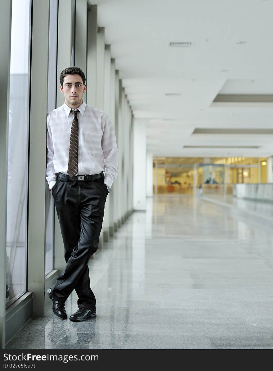 Handsome young man in business suit standing in office environment. Handsome young man in business suit standing in office environment