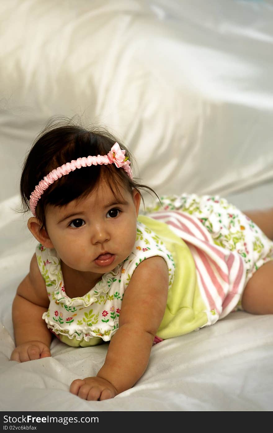 Baby on stomach looking and smiling wearing yellow baby wear. Baby on stomach looking and smiling wearing yellow baby wear