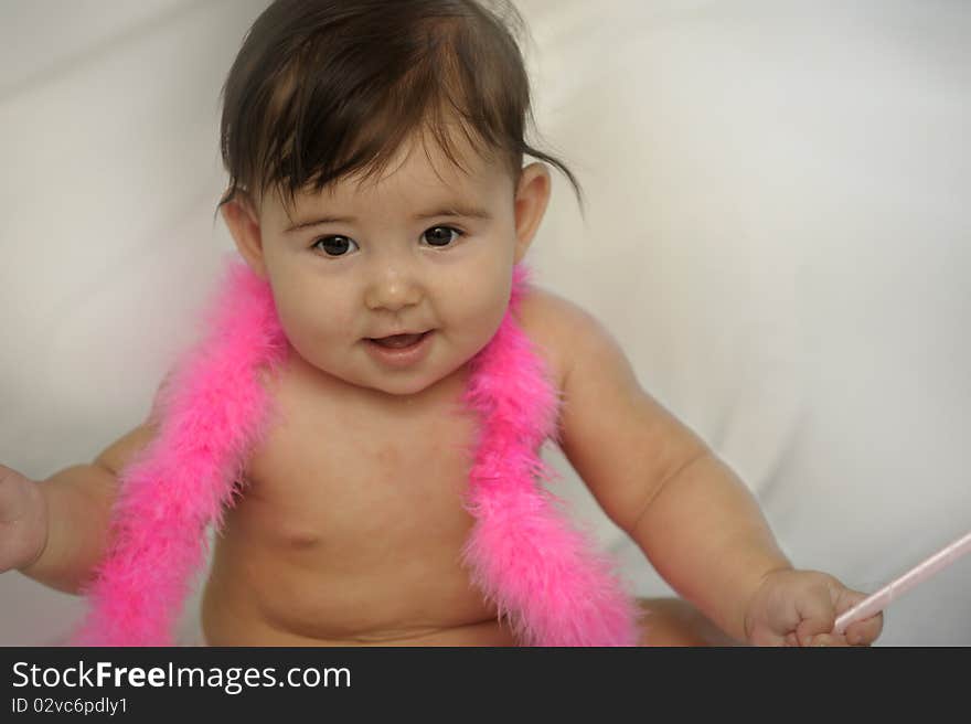 Naked baby girl sitting and smiling with pink