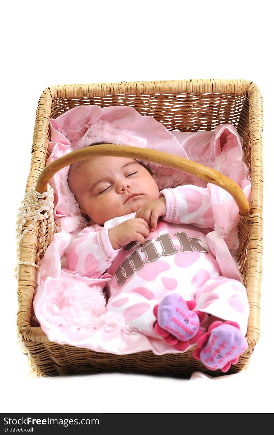 Baby girl in pink dots laying in a brown basket draped with white beads. Baby girl in pink dots laying in a brown basket draped with white beads