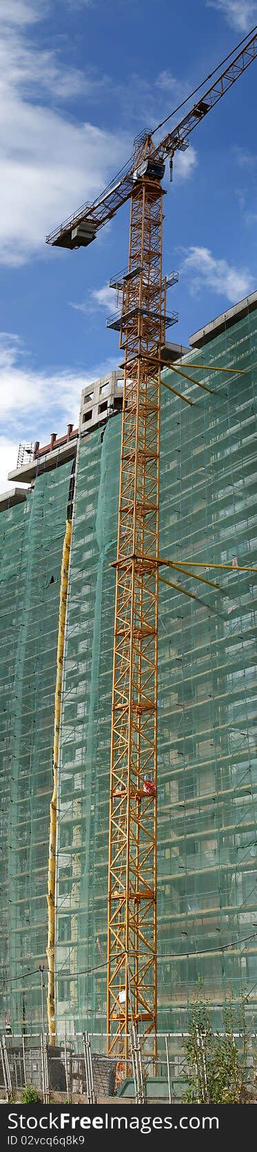 Building crane at the background of a multi-storey building under construction