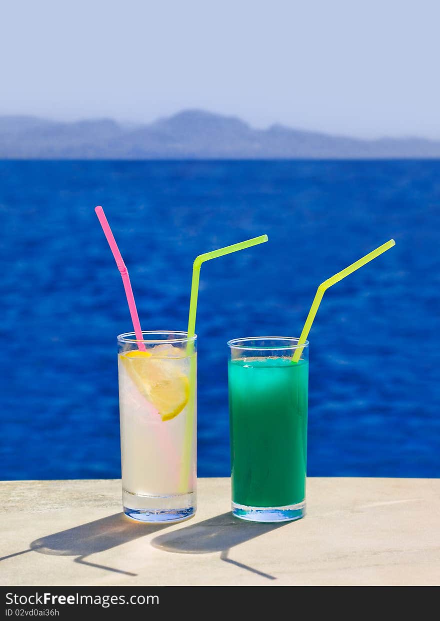 Two cocktails on marble table at beach - travel background