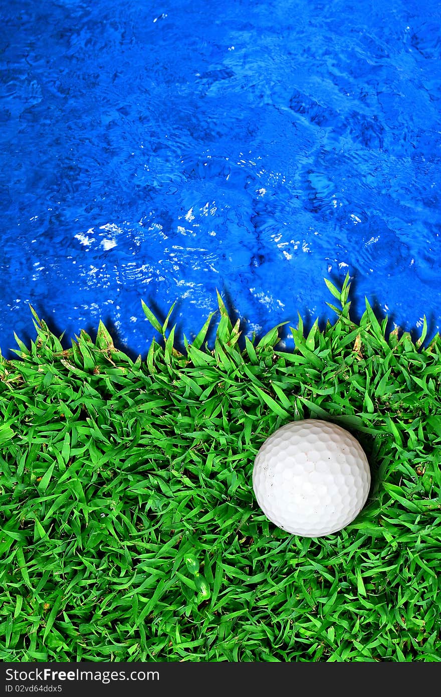 Golf ball on green grass near blue water