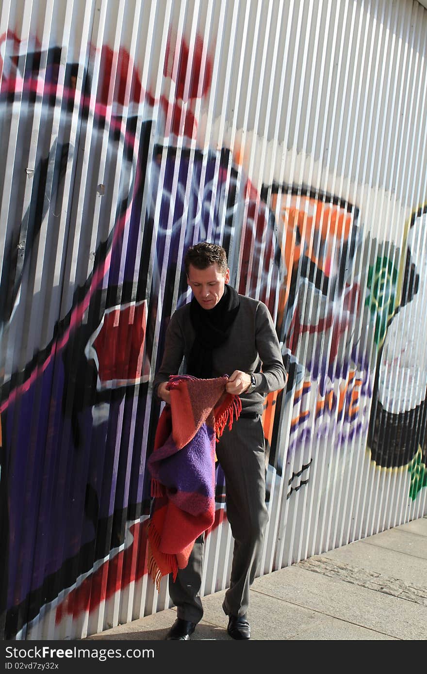 Man putting blanket to ground near graffity wall. Man putting blanket to ground near graffity wall.