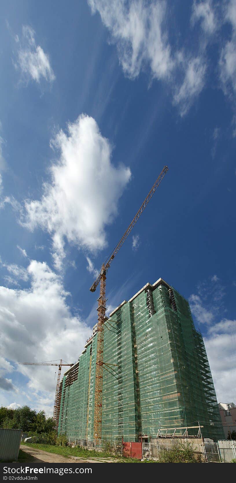 Elevating construction crane against the background of house under construction