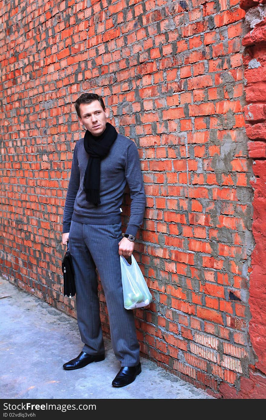 Man with apples standing near brick wall. Man with apples standing near brick wall.