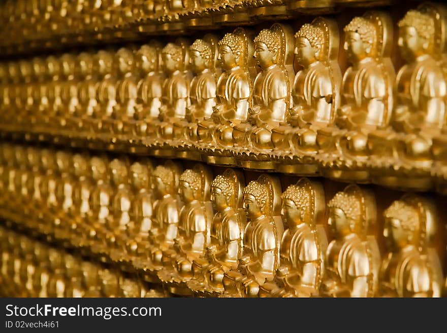 Many golden buddha image on wood wall perspective