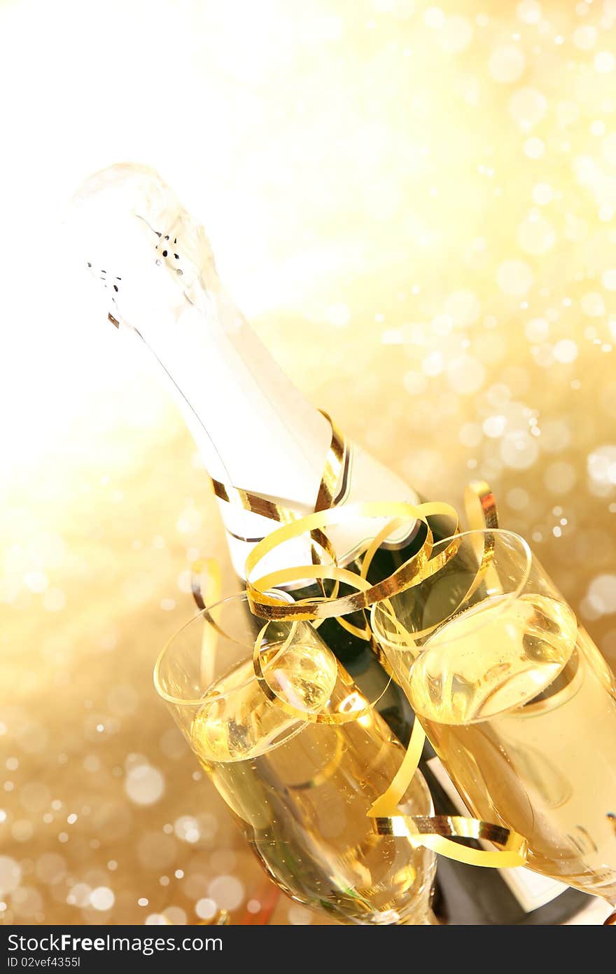 Studio photo of champagne glasses with bottle and golden decoration on background. Studio photo of champagne glasses with bottle and golden decoration on background