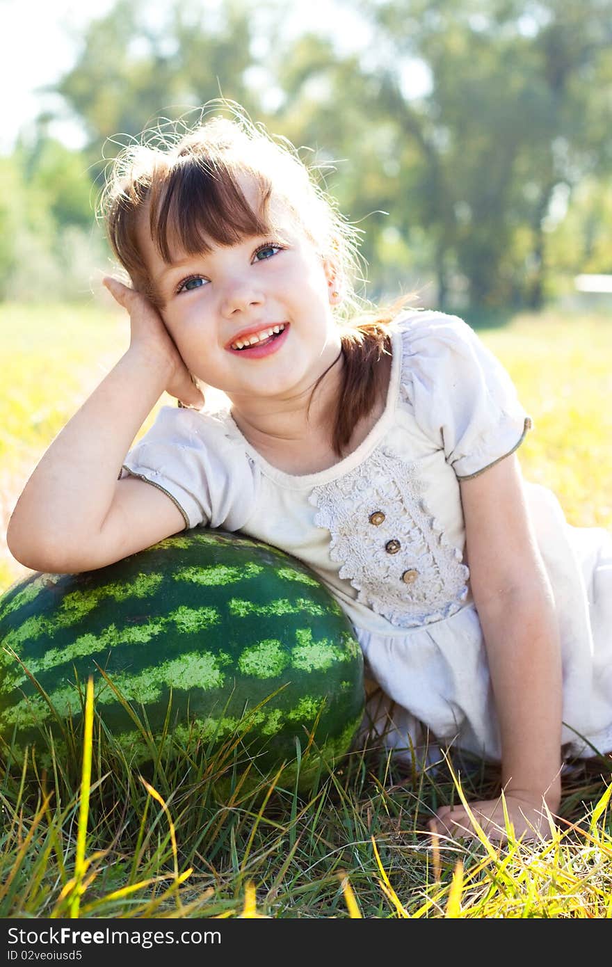 Beautiful little girl lying in meadow, leaning against a watermelon and dreams. Beautiful little girl lying in meadow, leaning against a watermelon and dreams