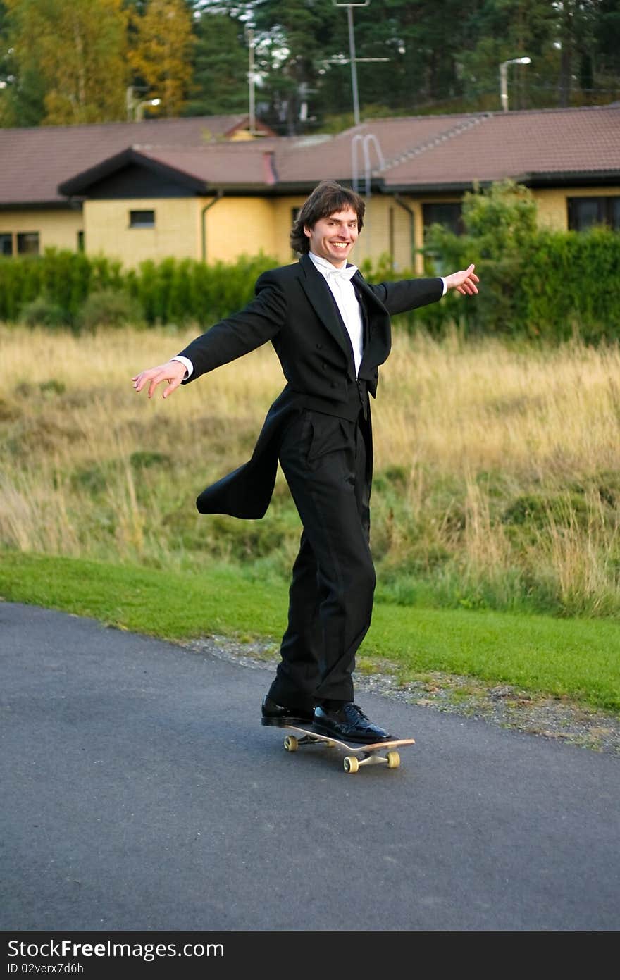 A man in tuxedo on a scateboard. A man in tuxedo on a scateboard