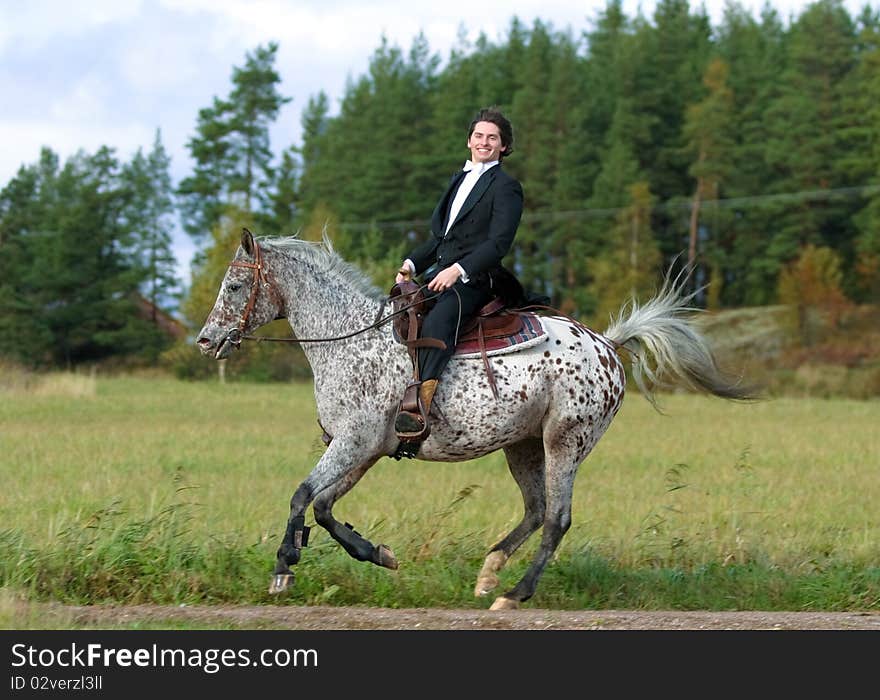 A man in tuxedo riding appaloosa mare with western tack. A man in tuxedo riding appaloosa mare with western tack