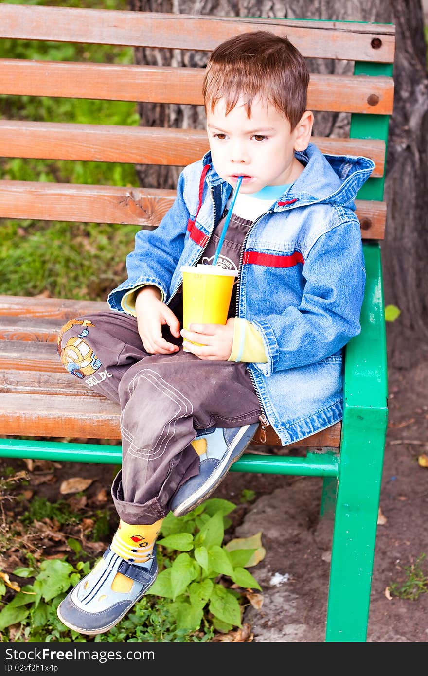 A little boy thinks and drinking with a glass tube. A little boy thinks and drinking with a glass tube