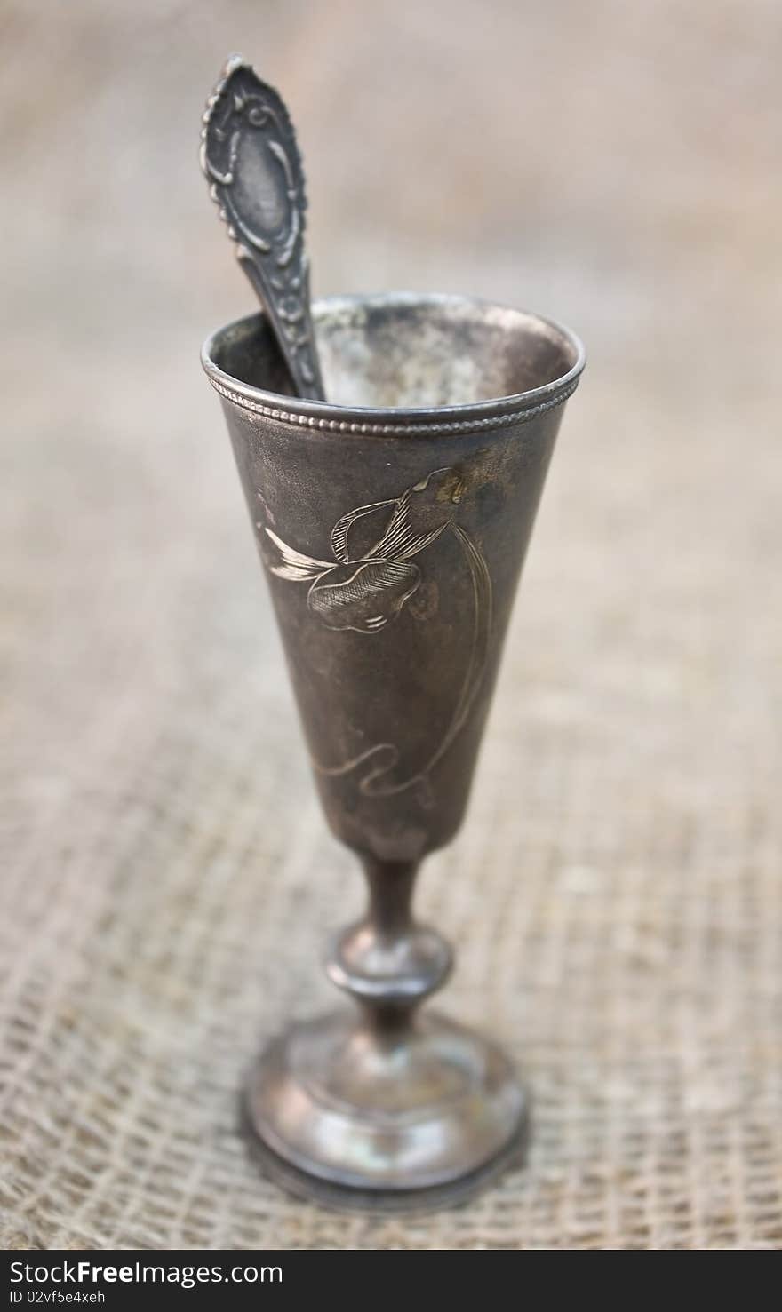 Silver goblet with silver spoon on sacking