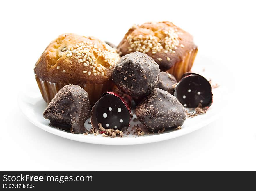 Tasty muffin, chocolate sweet cone and truffle with shaving on plate over white