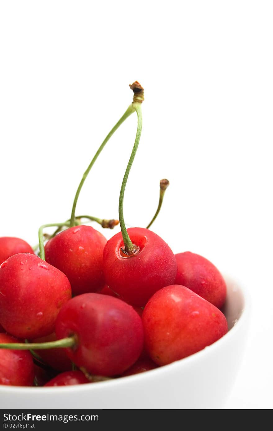 Fresh cherries in white bowl over white