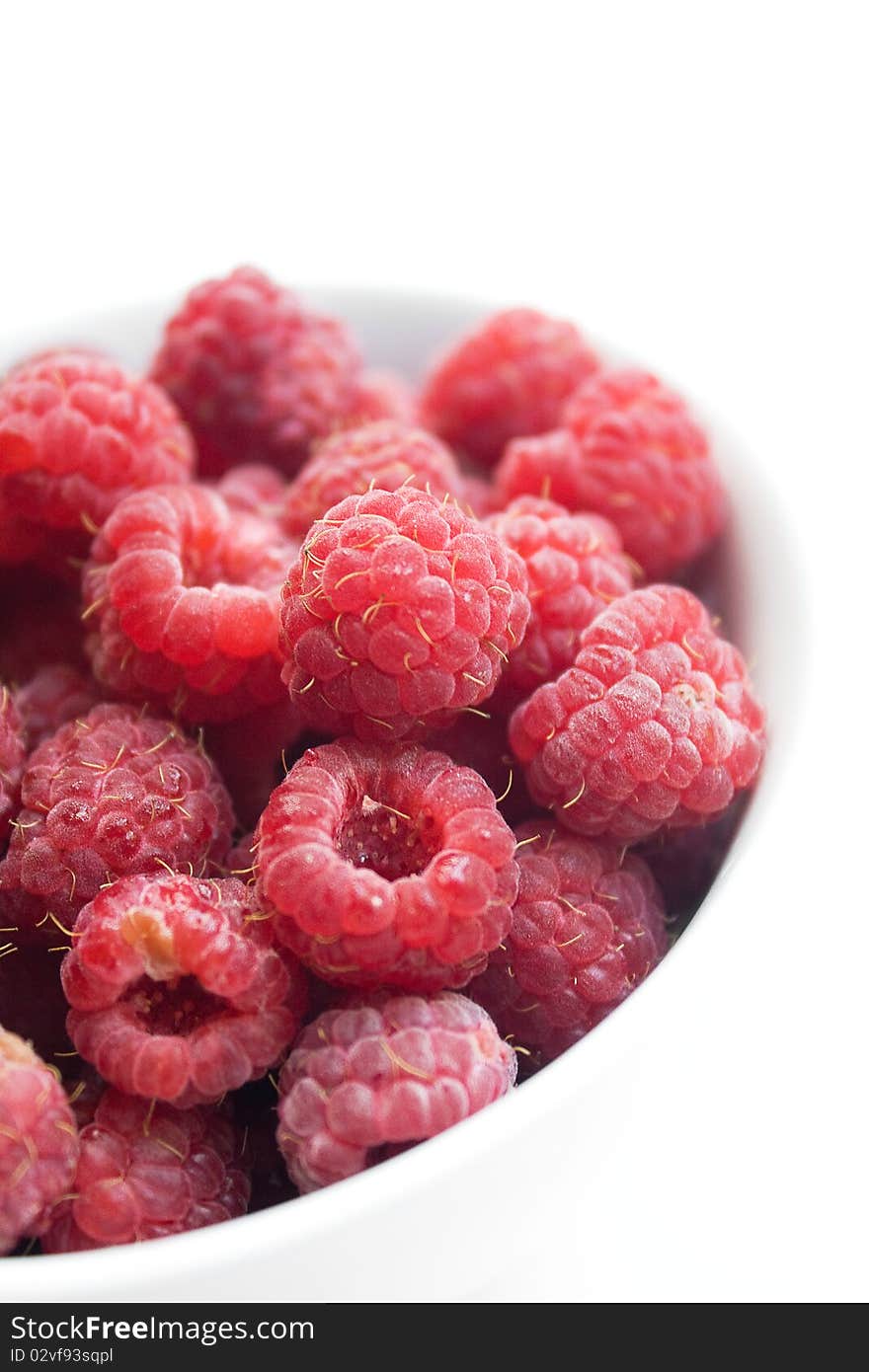 Fresh raspberries in white bowl over white background